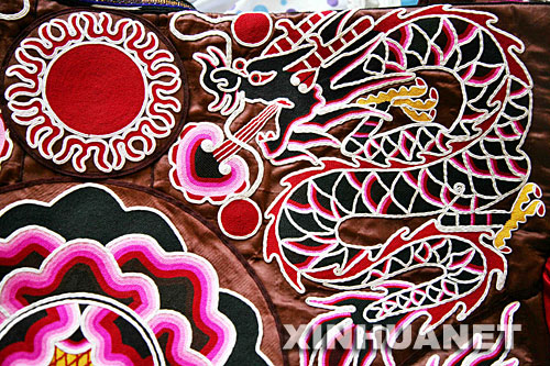 10月9日拍摄的一件标价8万元的苗族刺绣盛装上的图案。 当日,在2007多彩贵州旅游商品设计大赛和旅游商品制作能工巧匠选拔大赛总决赛上,来自凯里市的苗族妇女王金花手工制作的一件精美刺绣苗装标出8万元的高价,吸引了众多参赛者和市民的眼球。据介绍,这件苗族盛装采用叠绣、平绣、扁带绣、打籽绣、挑绣等多种绣法,以太阳、龙、凤、蝴蝶等为题材,为苗绣中的精品。