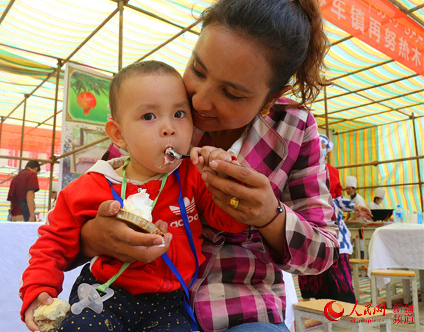 小朋友在妈妈的帮助下吃蛋糕。冉波 摄